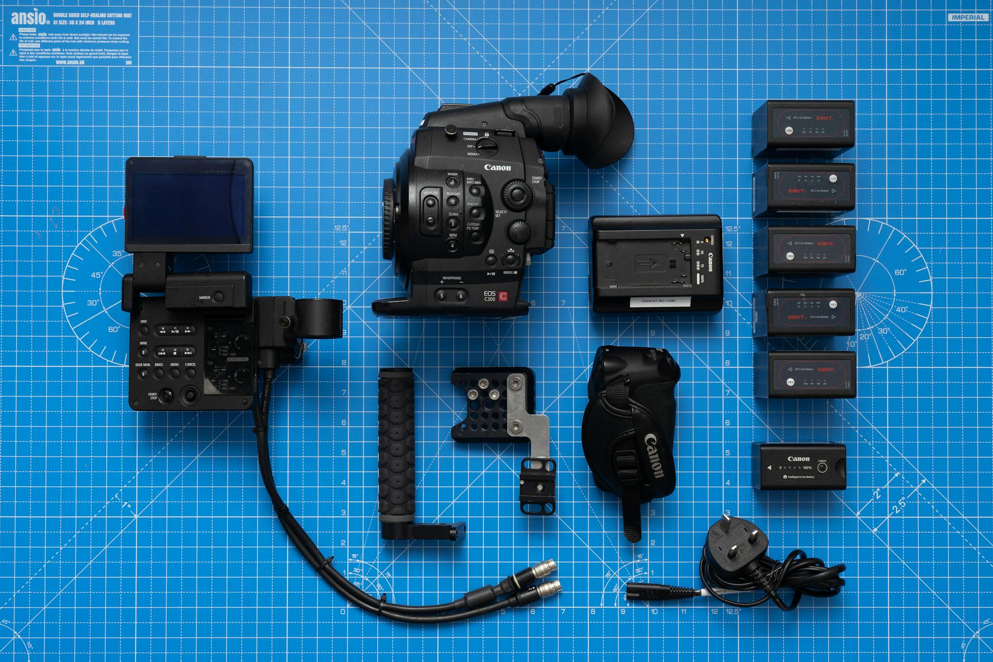 Flat lay image of Canon cinema camera equipment and accessories on a blue mat.
